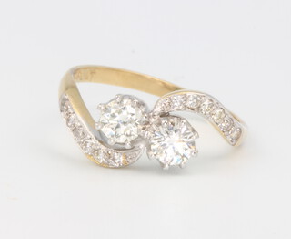An 18ct yellow gold Edwardian style 2 stone diamond cross-over ring, the 2 brilliant cut diamonds approx. 0.95ct with brilliant cut diamonds to the shoulders, size M 