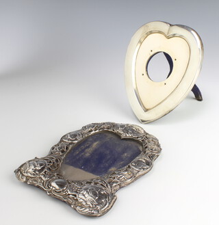 An Edwardian repousse silver heart shaped photograph frame, the border with Reynolds angels and scrolling flowers 19cm, a plain silver heart shaped ditto 17cm (both with rubbed marks) 