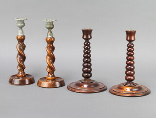 A pair of turned teak candlesticks formed from teak removed from HMS Britannia 23cm h x 15cm, together with a pair of 1930's oak spiral turned candlesticks with metal sconces 25cm h x 10cm with cork base marked Genuine Yangarran Ware  
