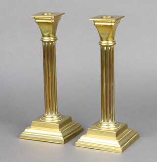 A pair of brass reeded candlesticks with detachable sconces raised on square stepped bases 24cm h x 9cm x 9cm 