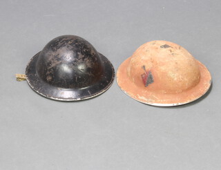 A Second World War Royal Artillery steel helmet with flash, painted to the side, together with a black painted Second World War steel helmet