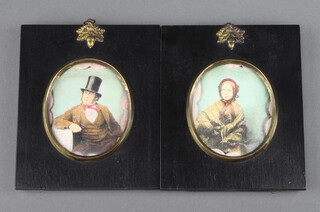 A pair of oval coloured prints of a seated lady and gentleman in ebonised and gilt mounted frames 7cm x 6cm 