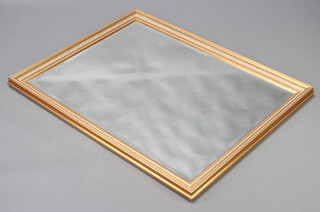 A rectangular bevelled plate mirror contained in a decorative gilt frame 114cm h x 87cm w 