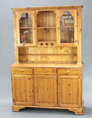 Ducal, a pine dresser with raised back fitted a recess, flanked by cupboards enclosed by glazed panelled doors, the base fitted drawers above a triple cupboard, raised on bracket feet 193cm h x 131cm w x 44cm d 
