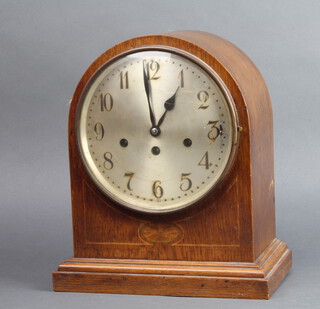 An Edwardian striking bracket clock with silvered dial and Arabic numerals contained in an inlaid oak, arch shaped case (missing bun feet), complete with key and pendulum 
