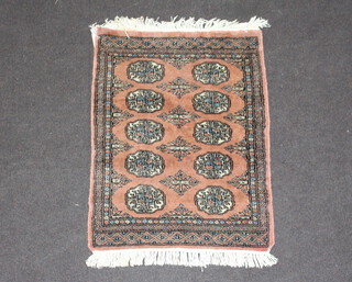 A pink ground Bokhara rug with 10 octagons to the centre 87cm x 64cm (some staining to the edge)