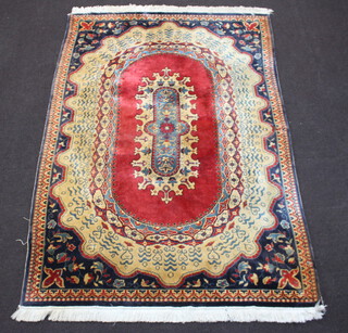 A machine made red, gold and blue ground Persian style carpet with oval central medallion 