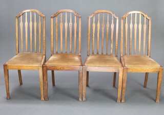 A set of 4 Edwardian oak stick and rail back dining chairs with upholstered drop in seats, raised on square supports 