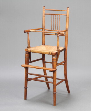 A Victorian elm stick and rail back child's high chair with woven rush seat raised on turned supports 
