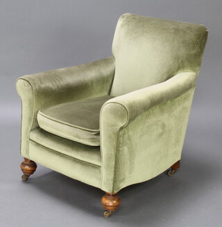 A Howard style armchair upholstered in green Dralon, raised on bun feet 