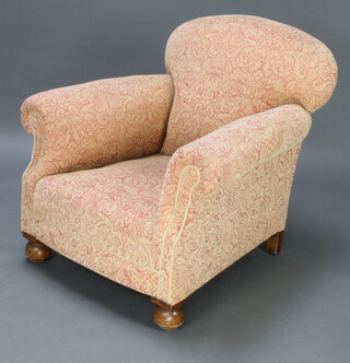 A Victorian armchair upholstered in red and white floral material, raised on bun feet 