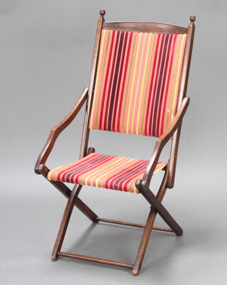 An Edwardian mahogany folding campaign armchair upholstered in striped material  