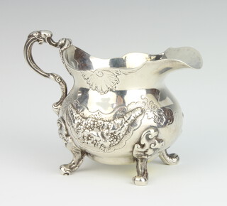A Victorian repousse silver cream jug decorated with flowers and grapes on scroll feet London 1839, 236 grams