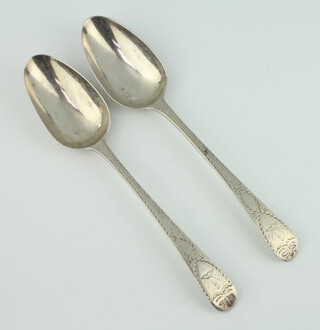 A pair of Georgian silver bright cut serving spoons with engraved crest, 140 grams