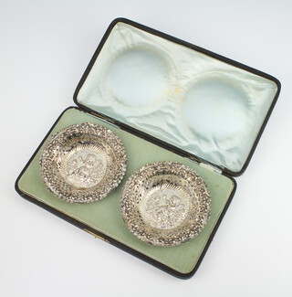 A pair of Edwardian pierced and repousse silver circular dishes decorated with cherubs, Birmingham 1901, 12cm, 67.5 grams, contained in a fitted case 