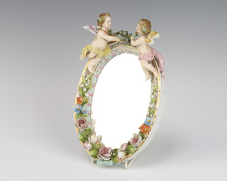 A German porcelain oval dressing table mirror decorated with flowers and surmounted by 2 angels with bevelled plate 24cm 