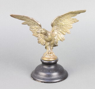 A gilt metal "car mascot" in the form of an eagle with wings outstretched, raised on an ebonised socle base 15cm h x 16cm w 