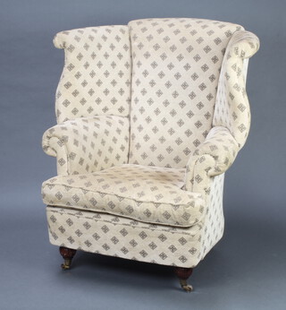 A Georgian style winged library chair upholstered in yellow material raised on turned bun feet, brass caps and castors 