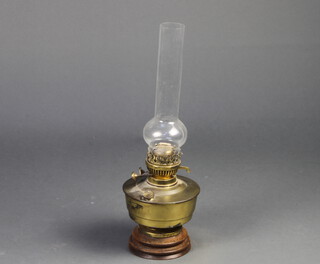 A brassed oil lamp reservoir with clear glass chimney 50cm x 16cm together with an aneroid barometer and thermometer contained in a carved oak wheel case