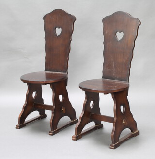 A pair of Swiss style mahogany hall chairs raised on pierced panelled supports 