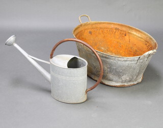 An oval galvanised metal twin handled bath 29cm x 70cm x 55cm together with a watering can 28cm h 