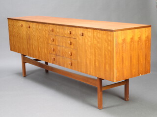 A Heals style teak sideboard a fitted cupboard and cocktail unit with fall front, flanked by 4 drawers and cupboard enclosed by a panelled door 78cm h x 214cm w x 46cm d 