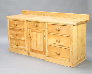 A Victorian pine dresser base with raised back, fitted a drawer above a cupboard flanked by drawers to each side, raised on a platform base 85cm h x 167cm w x 49cm d 