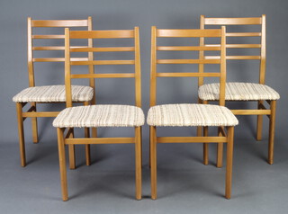 A mid Century set of 4 teak ladder back dining chairs raised on square supports 