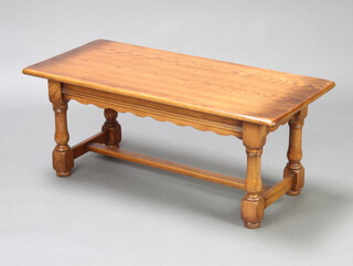 A rectangular oak occasional table raised on turned supports with H framed stretcher 42cm h x 99cm w x 46cm d 