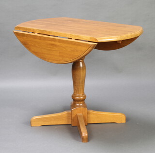 A "beech" oval drop flap pedestal dining table raised on a turned column and cruciform supports 73cm h x 90cm x 54cm 
