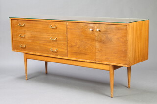 Uniflex, a mid Century teak sideboard fitted 3 drawers flanked by cupboards on turned supports 79cm h x 169cm w x 46cm d 
