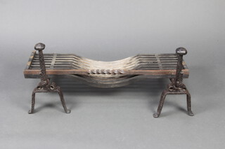 A pair of wrought iron fire dogs 38cm x 54cm x 20cm, together with a basket 18cm x 87cm x 34cm  