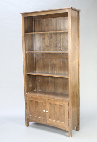 An oak bookcase fitted adjustable shelves, base enclosed by panelled doors 199cm h x 95cm w x 34cm d 