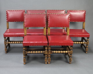 A set of 6 oak dining chairs, the seats and backs upholstered in red material, raised on turned and block supports 