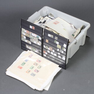 A collection of mint and used world stamps in a grey plastic crate 