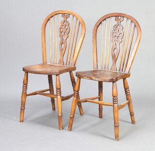 Two elm stick and wheel back dining chairs on turned supports with H framed stretchers 