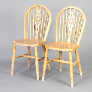 A pair of beech framed stick and wheel back dining chairs on turned supports with H framed stretcher  