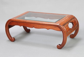 A Chinese hardwood opium table/coffee table with plate glass top and raised on scroll supports 41cm x 104cm x 55cm