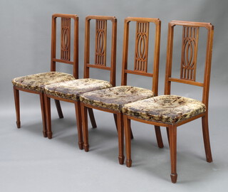 A set of 4 Edwardian inlaid mahogany stick and rail back dining chairs with over stuffed seats, raised on square tapered supports, spade feet 