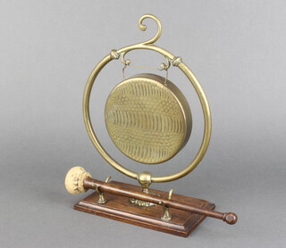 An Edwardian brass bell on an oak plinth with beater