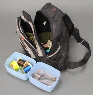 A black fabric rucksack containing sea fishing reels, weights, etc, 