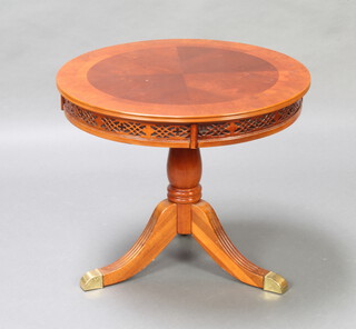 A Georgian style mahogany circular quarter veneered and crossbanded revolving occasional table with blind fretwork frieze raised on pillar and tripod base with brass caps and castors 56cm h x 66cm diam. 