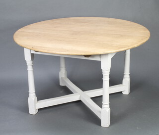 A light oak circular extending dining table, the white painted base raised on turned column and X framed stretcher 75cm h x 130cm diam. (no leaves to this table) 