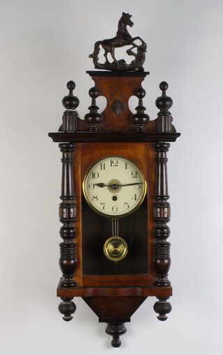 A regulator style timepiece with paper dial and Arabic numerals, gridiron pendulum, contained in a walnut case surmounted by a figure of a horse, complete with key 