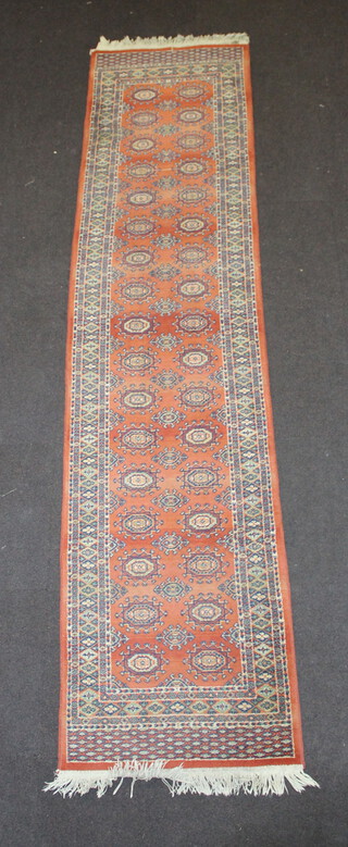 A machine made orange and white ground Bokhara style runner with 34 octagons to the centre 302cm x 69cm 