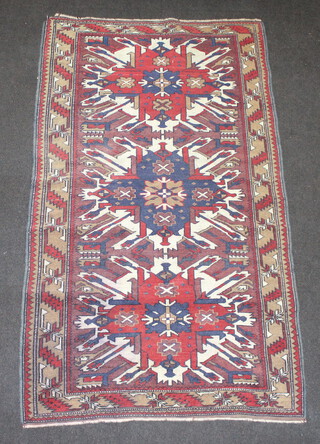 A red white and blue Afghan rug with 3 stylised medallions within a multi row border 194cm x 109cm 