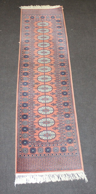 A tan and white ground machine made Bokhara style runner with 13 octagons to the centre 270cm x 68cm  