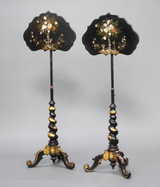 A pair of Victorian ebonised and gilt painted pole screens with shaped papier mache screens, raised on spiral turned columns and tripod bases 32cm h x 50cm w 