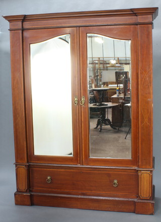 An Edwardian inlaid mahogany double wardrobe with moulded cornice enclosed by a pair of arched panelled doors, the base fitted a drawer raised on a platform base 207cm h x 159cm w x 54cm d 