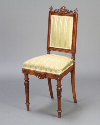 A Victorian walnut nursing chair with carved cresting rail and finials, upholstered seat and back, raised on carved and fluted supports 